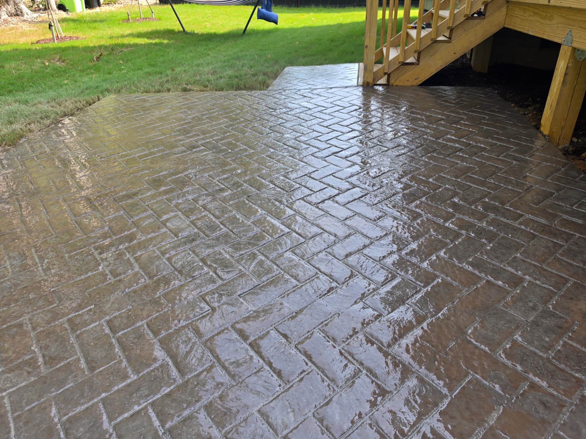 Sealed stamped concrete patio surrounding wooden deck steps
