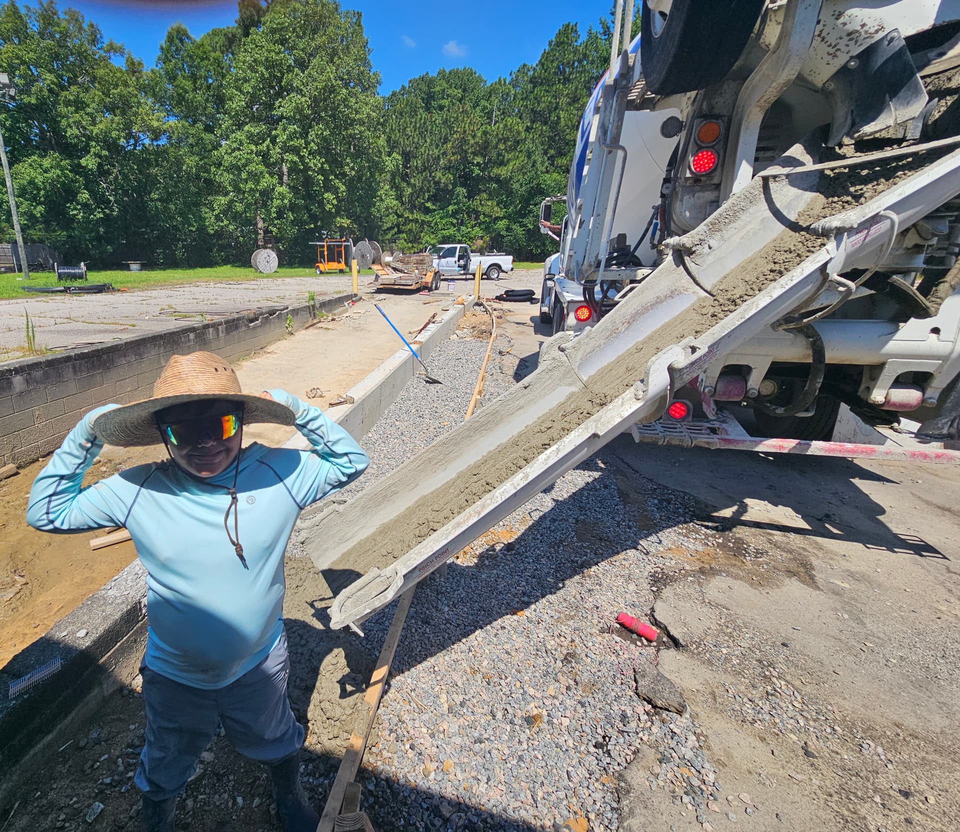 Person in a straw hat beside a concrete mixer truck during a concrete pour