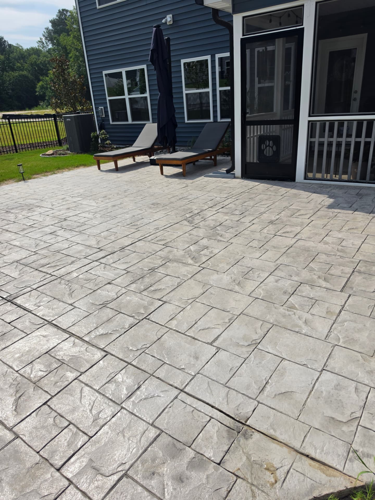 Gray stamped concrete patio beside a screened porch
